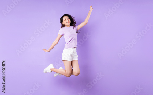 Young asian girl jumping up on purple background © 1112000