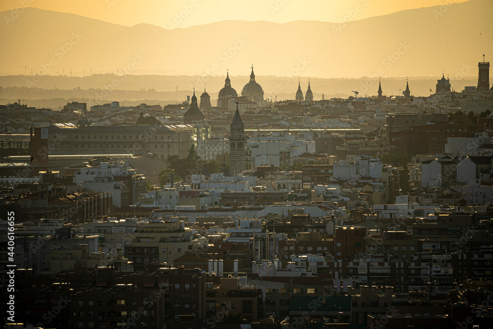 Puesta de sol en la ciudad de Madrid con vistas a los edificios y pequeñas nubes con el horizonte anaranjado, atardecer.