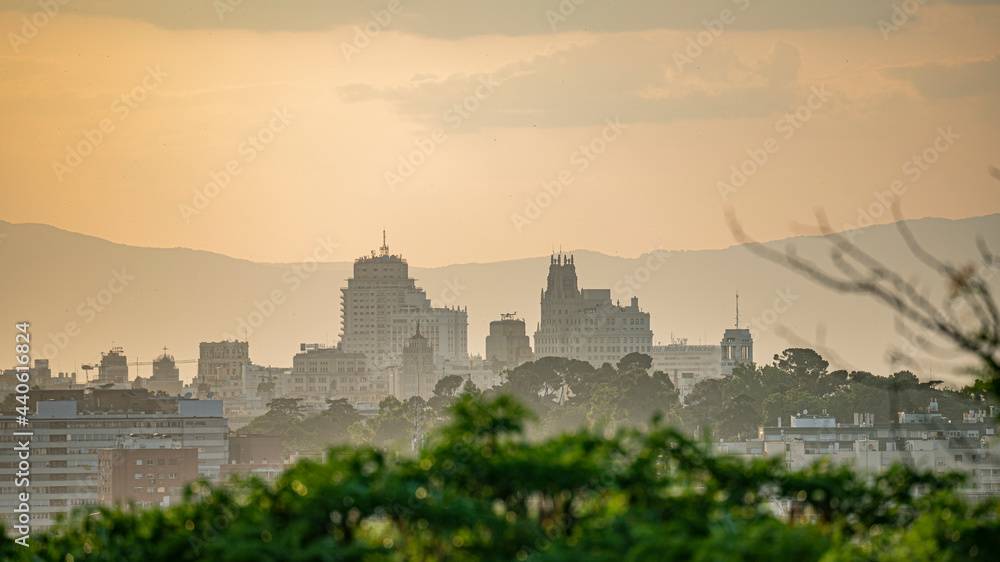 Puesta de sol en la ciudad de Madrid con vistas a los edificios y pequeñas nubes con el horizonte anaranjado, atardecer. Puesta de sol en la ciudad de Madrid con vistas a los edificios y pequeñas nubes con el horizonte anaranjado, atardecer.