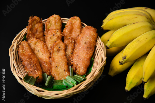 Homemade tasty fried Banana in basket Sprinkle with pandan leaves and white sesame and Black background.