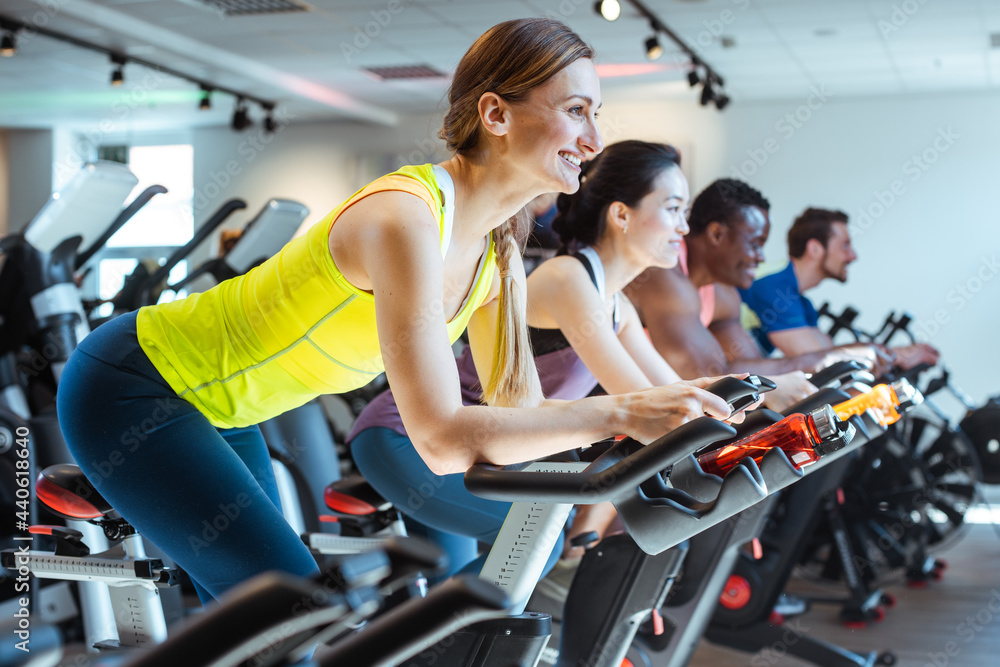 Very fit Caucasian woman and her friends on fitness bike in gym Very fit Caucasian woman and her friends on fitness bike in gym