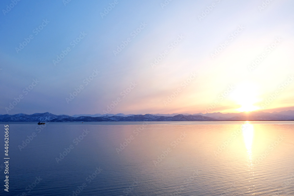 Sunset view of the Avacha Bay. Ships standing in the roadstead, mountains in the background. Petropavlovsk-Kamchatsky, Kamchatka Peninsula, Russia.