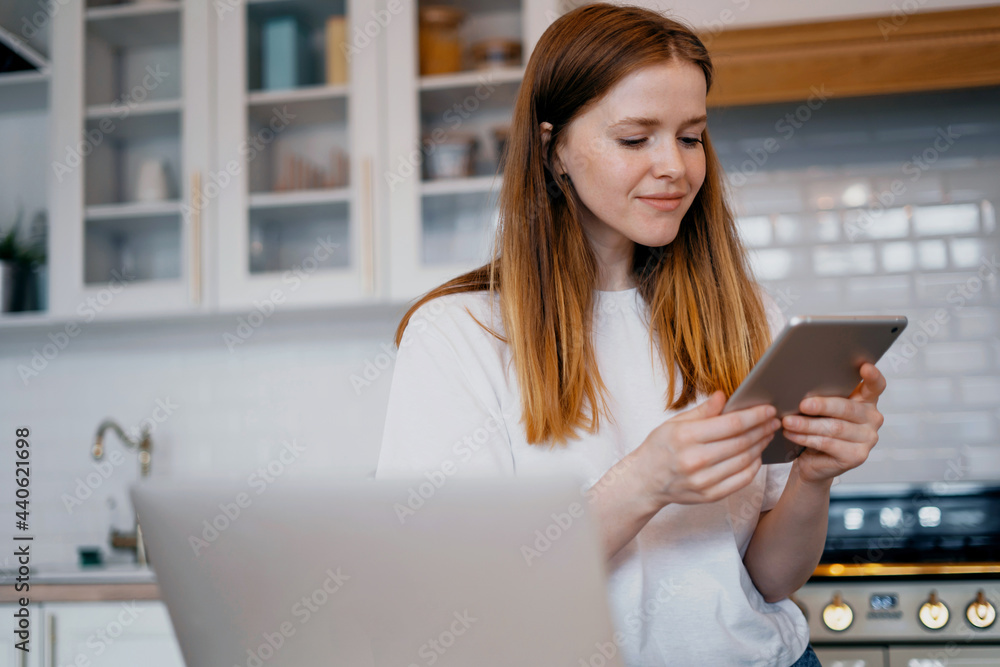 Applies for a mortgage loan online at the bank. A satisfied housewife types an email message to the bank on her laptop. The woman is a young red-haired European-looking student. Applies for a mortgage loan online at the bank. A satisfied housewife types an email message to the bank on her laptop. The woman is a young red-haired European-looking student.