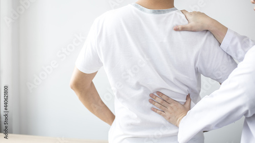 Physical therapy, Female physiotherapist treats back pain for a male patient attending a rehabilitation center, Bone arrangement, Non-surgical medical treatment, Modern medical techniques.