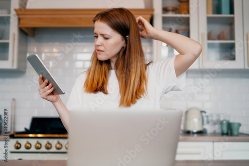 Student learning in a laptop in the kitchen. A freelancer sits in an apartment and works on a laptop. Young woman shopping online ordering home groceries.