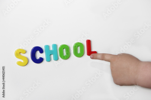 the back to school concept.The beginning of the new school year. the child reads the word school, pointing with his finger photo