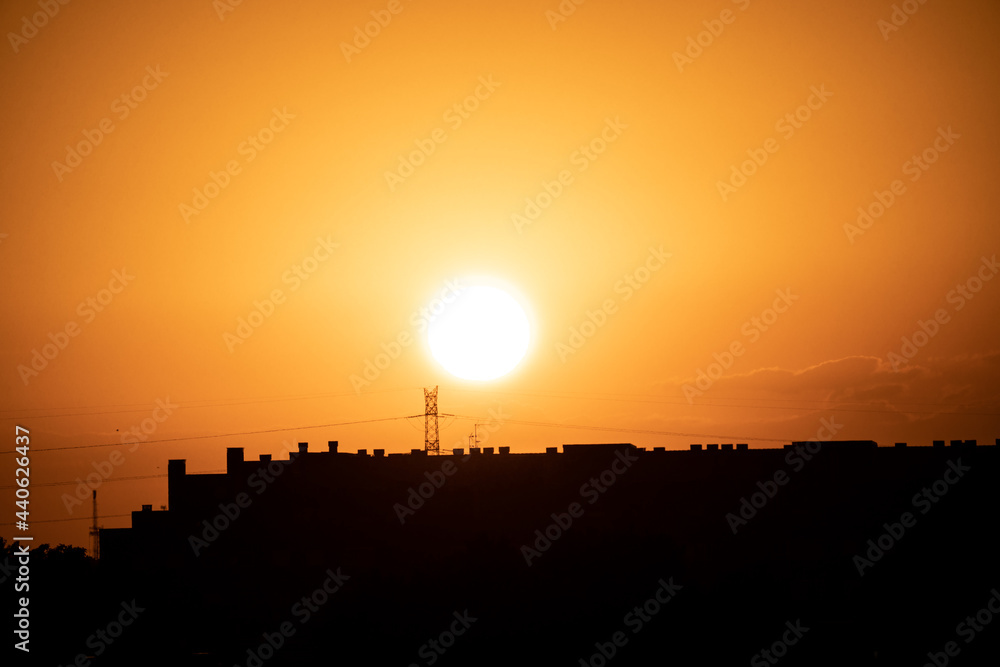 Puesta de sol en la ciudad de Madrid con vistas a los edificios y pequeñas nubes con el horizonte anaranjado
