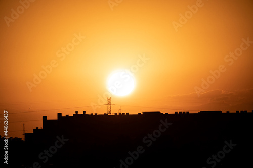 Puesta de sol en la ciudad de Madrid con vistas a los edificios y pequeñas nubes con el horizonte anaranjado