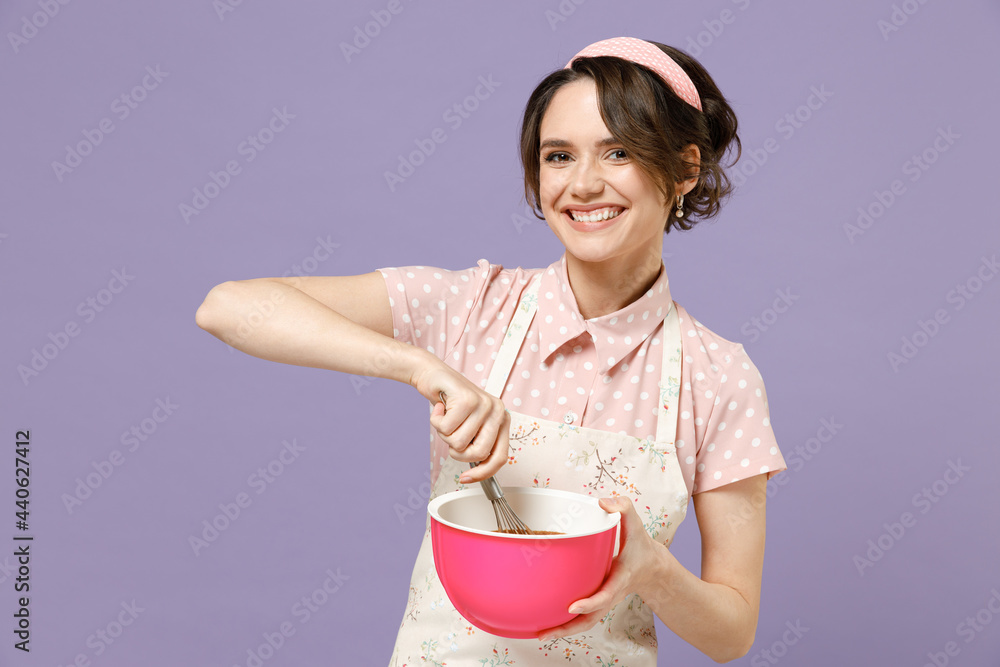 Young smiling happy cheerful housewife housekeeper chef cook baker woman in pink apron beating egg yolks whites look camera isolated on pastel violet background studio portrait Cooking food concept Young smiling happy cheerful housewife housekeeper chef cook baker woman in pink apron beating egg yolks whites look camera isolated on pastel violet background studio portrait Cooking food concept