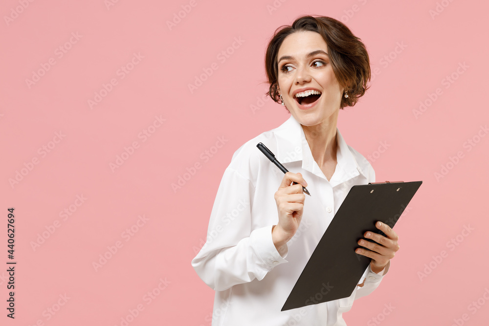 Young fun successful employee business secretary woman corporate lawyer in classic formal white shirt work in office clipboard with papers write document look aside isolated on pastel pink background. Young fun successful employee business secretary woman corporate lawyer in classic formal white shirt work in office clipboard with papers write document look aside isolated on pastel pink background.