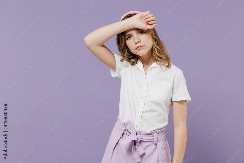 Little sad tired sick exhausted blonde kid girl 12-13 years old in white shirt put hand on forehead have headache isolated on purple background children studio portrait. Childhood lifestyle concept. Little sad tired sick exhausted blonde kid girl 12-13 years old in white shirt put hand on forehead have headache isolated on purple background children studio portrait. Childhood lifestyle concept.