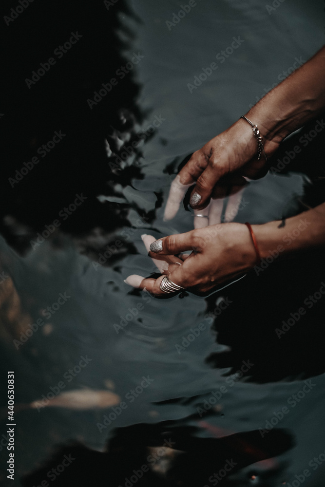 Female hands inside the dark water of the pond