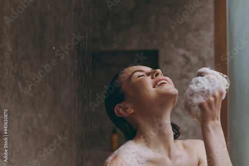 Canvas Print Relaxed half naked topless young woman 20s take hot shower use blue washcloth with closed eyes in bathroom do morning routine in brown background