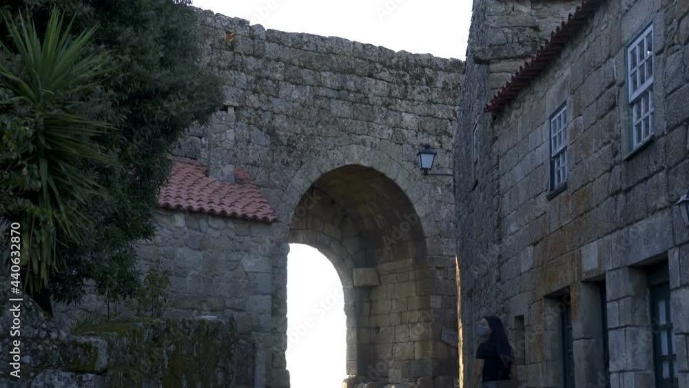 Woman traveler in Sortelha historic village castle gate entrance at sunset on a traditional antique stone street, Portugal Woman traveler in Sortelha historic village castle gate entrance at sunset on a traditional antique stone street, Portugal