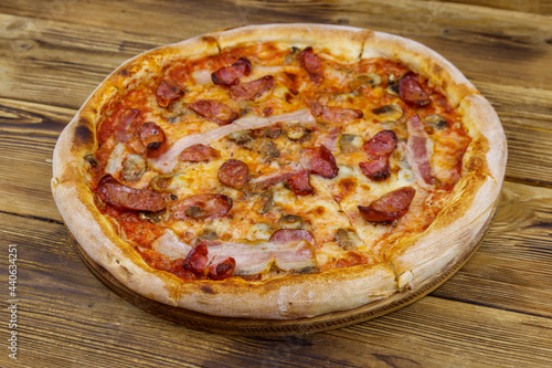 Delicious fresh pizza with sausage, mushrooms and cheese on a wooden table