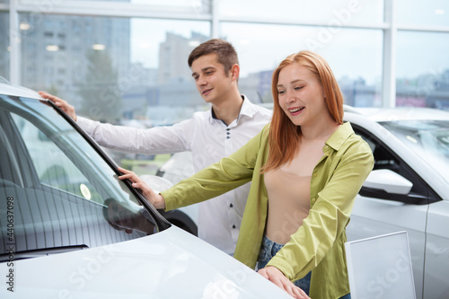 Young couple examining cars for sale at dealership salon © Ihor