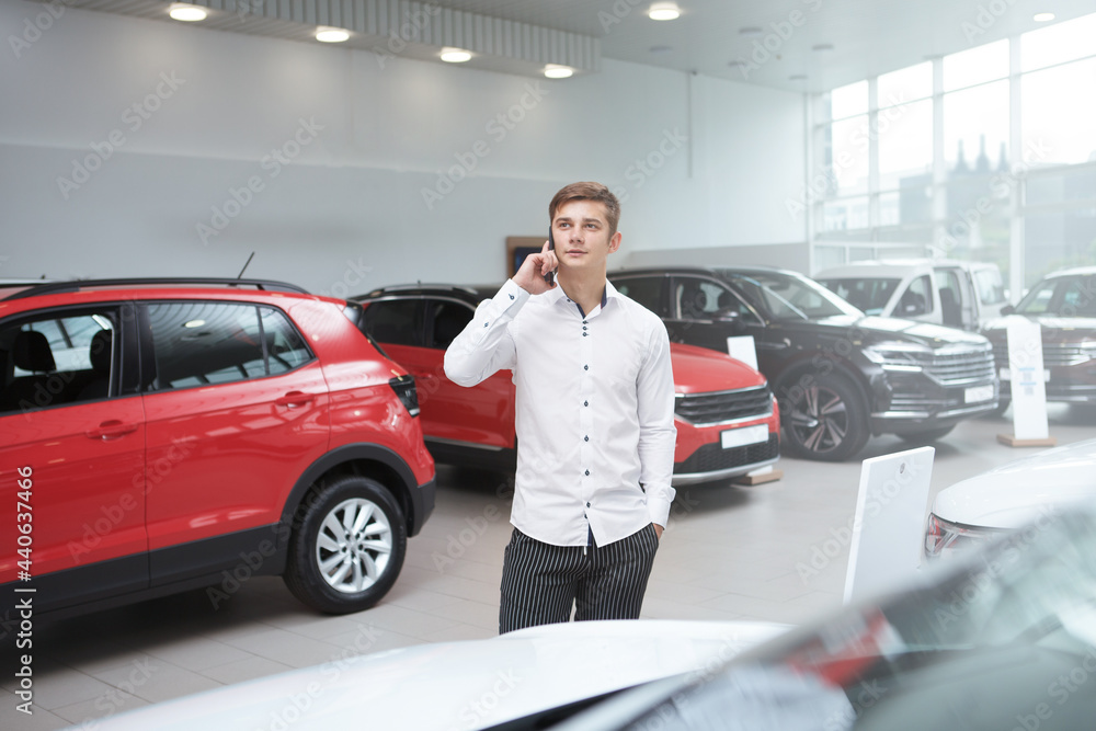 Male customer talking on his smart phone while choosing new auto to buy Male customer talking on his smart phone while choosing new auto to buy