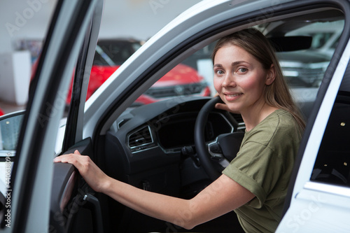 Cheerful female driver sitting in a new auto at car dealership © Ihor
