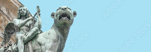 Photography Statue of a panther with genius of music, an angel with wings and a harp, stringed musical instrument at Concert Hall (Konzerthaus), in Berlin, Germany, with copy space as blue sky background