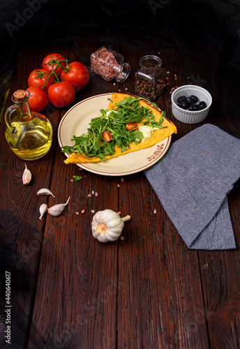 Typical Italian Farinata with with mozzarella, arugula, cherry tomatoes, and parmesan cheese on wooden table