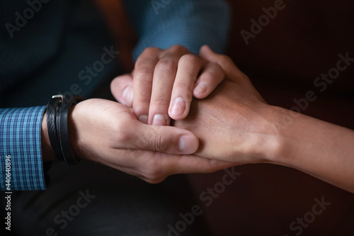 Close up sincere empathic young african ethnicity man covering hand of biracial woman, supporting in difficult life situation, giving psychological help, asking forgiveness or making peace indoors.