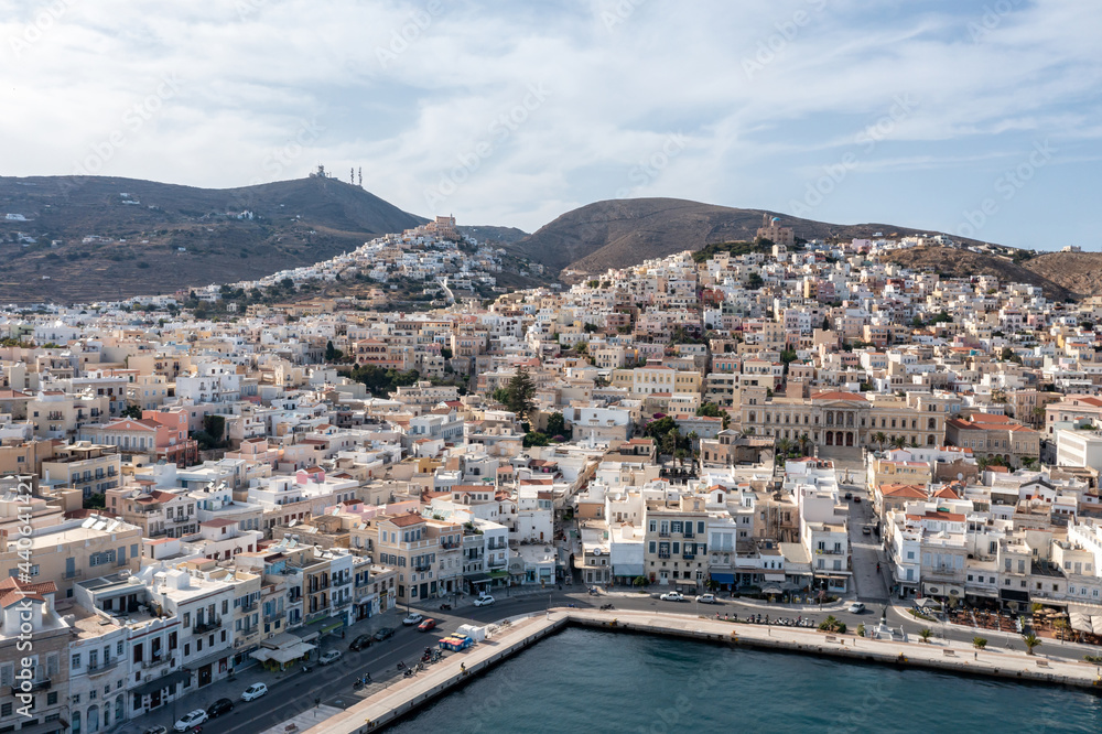 Syros island, Greece, aerial drone view. Ermoupolis and Ano Siros town cityscape, cloudy blue sky background.