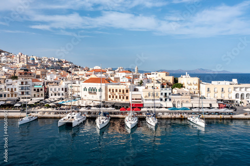 Fototapeta Naklejka Na Ścianę i Meble -  Syros island, Greece, aerial drone view. Saiboats moored at port dock, yachts marina. Ermoupolis town buildings background.