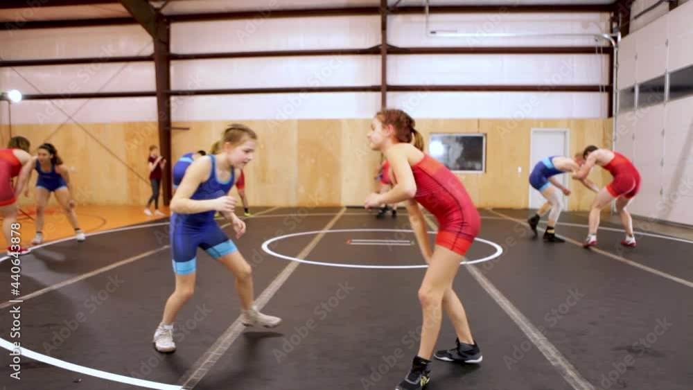 Pair of youth wrestlers drilling moves during a coed group wrestling practice. Pair of youth wrestlers drilling moves during a coed group wrestling practice.