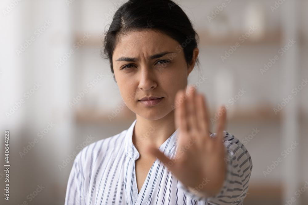 Portrait of unhappy distressed young Indian woman show stop no hand gesture sign against domestic violence. Determined mixed race ethnicity female protest against discrimination. Diversity concept. Portrait of unhappy distressed young Indian woman show stop no hand gesture sign against domestic violence. Determined mixed race ethnicity female protest against discrimination. Diversity concept.