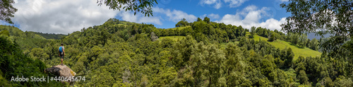Hiker in green landscape, trees and hills, Azores islands.