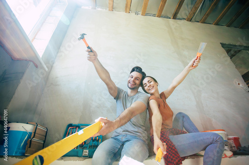 Modern happy young couple in love in casual clothes during new home repair or renovation of walls with a lot of tools for this © My Ocean studio