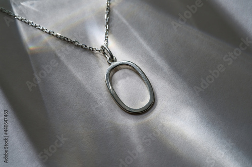 Neck chain with oval pendant on gray background