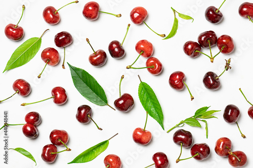 Fresh ripe cherries with leaves on white background top view. Bright cherry pattern.