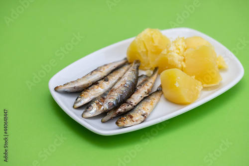 fried sardines with boiled potato on white dish