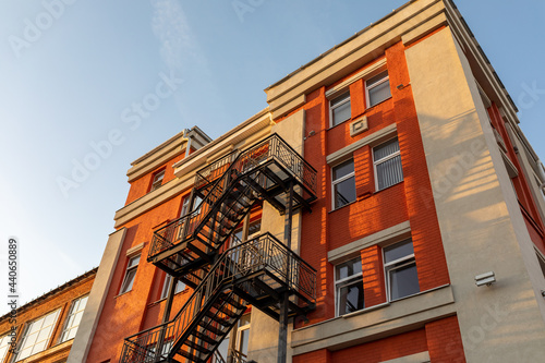 Black metal fire escape on the facade of an old brick building. Security concept, renovation. © LariBat