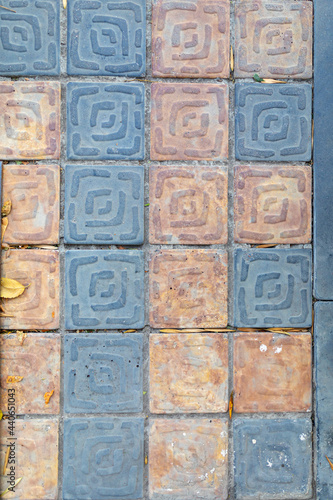 Sidewalk is covered with square blue and yellow paving slabs. Masonry texture.