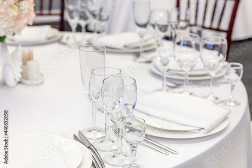 Fancy table set for dinner with napkin glasses in restaurant, luxury interior background. Wedding elegant banquet decoration and items for food arranged by catering service on white tablecloth table. © Юлия Завалишина