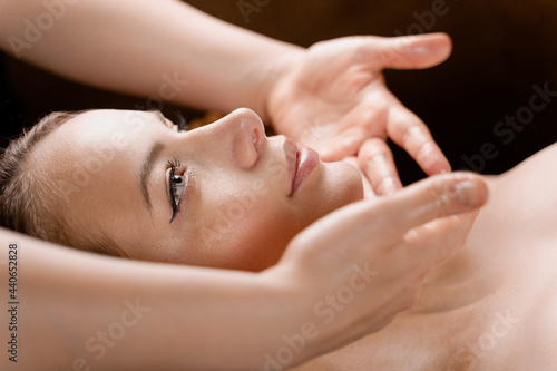 Facial massage close-up in spa center. Girl with perfect skin relaxing in massage room.