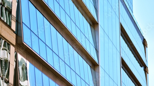 Abstract closeup of the glass-clad facade of a modern building covered in reflective plate glass. Architecture abstract background. Glass wall and facade detail.