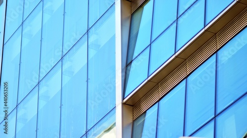 Abstract closeup of the glass-clad facade of a modern building covered in reflective plate glass. Architecture abstract background. Glass wall and facade detail.