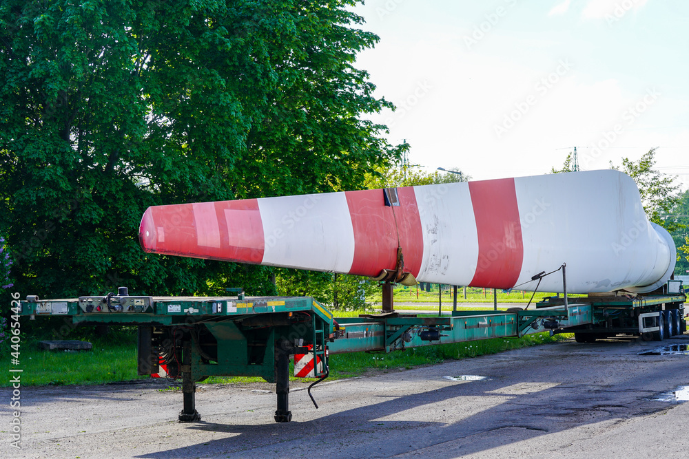 A view of a truck, a low-loader semi-trailer with oversized wind generator parts in the parking lot A view of a truck, a low-loader semi-trailer with oversized wind generator parts in the parking lot