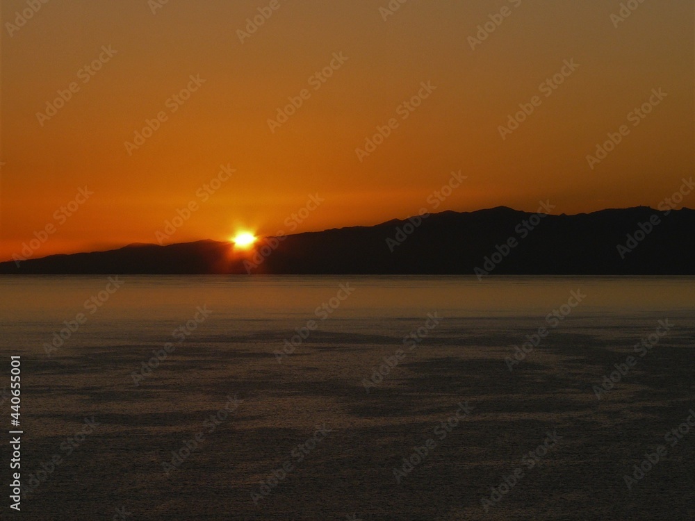 Sonnenuntergang über dem Meer mit Felsen und Sonne in orange