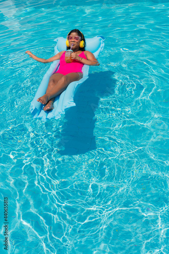 Black Woman sunbathing drinking a juice in a swimming pool