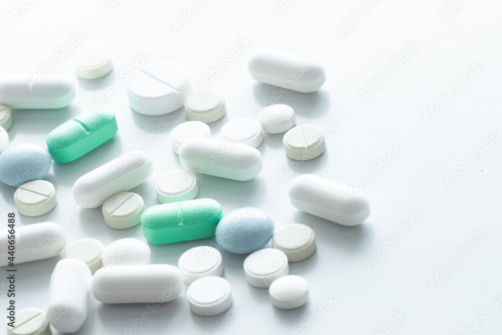 Colored pills are scattered on a white background. Medication treatment concept. Idea of a blog about health, vitamins, help with diseases. pharmacy business, benefits and harms of drugs.