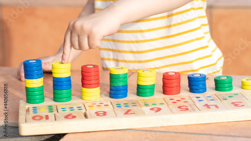 Math game for children. Children's hand plays with multi-colored rings. Natural materials, wooden. Score, number composition. Home education concept, early development, skills. Daylight. Outside.