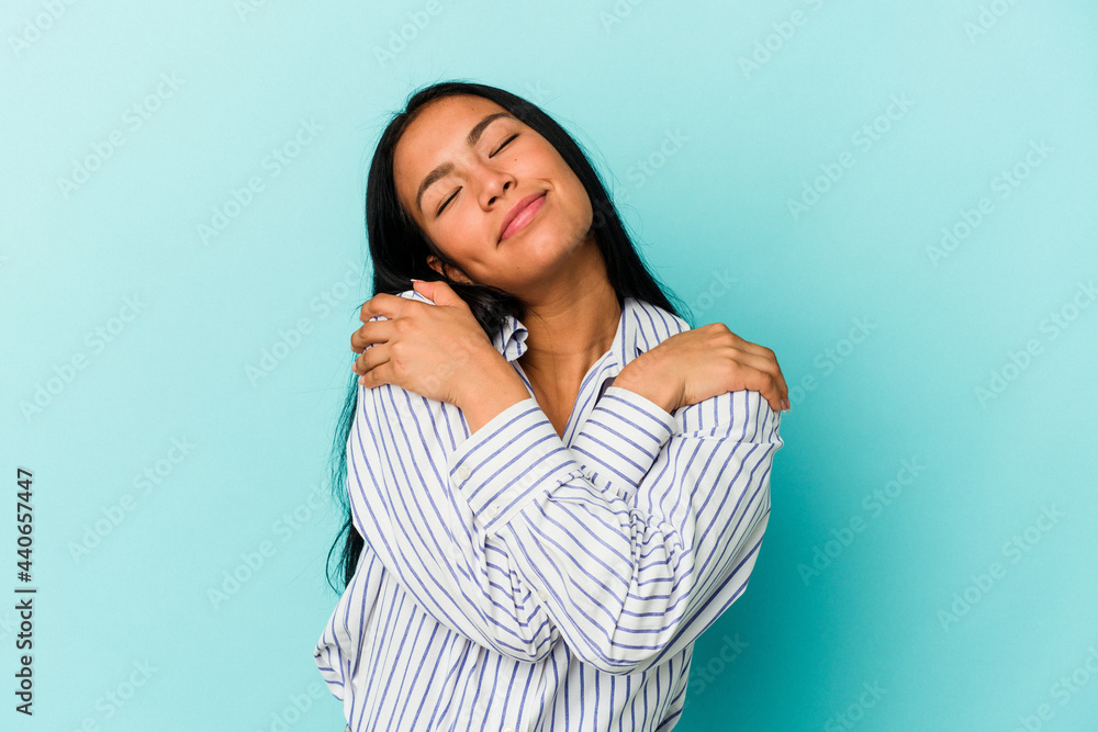 Young Venezuelan woman isolated on blue background hugs, smiling carefree and happy. Young Venezuelan woman isolated on blue background hugs, smiling carefree and happy.