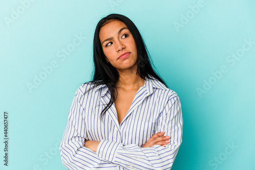 Young Venezuelan woman isolated on blue background dreaming of achieving goals and purposes © Asier