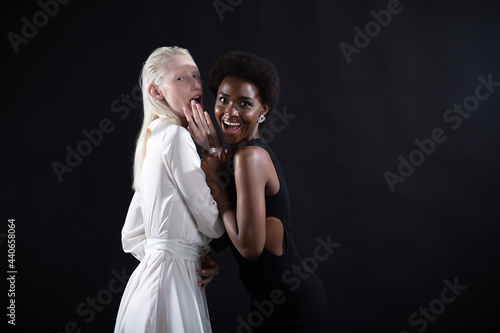 Caucasian albino girl and african american young woman hugging on black background. Women friendship, lgbt love and relationships concept.