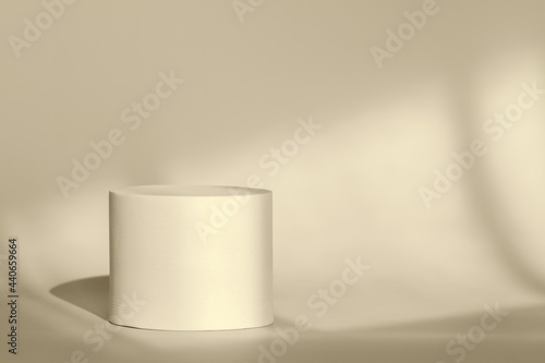 Beige round pedestal podium for packaging presentation on backdrop with room shadows from window.Circle platform stage for cosmetic products with geometric shadow on wall. Minimalist style © photo-lime