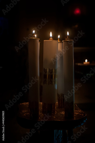 kilka płonących świec w kościele, pośród mroku